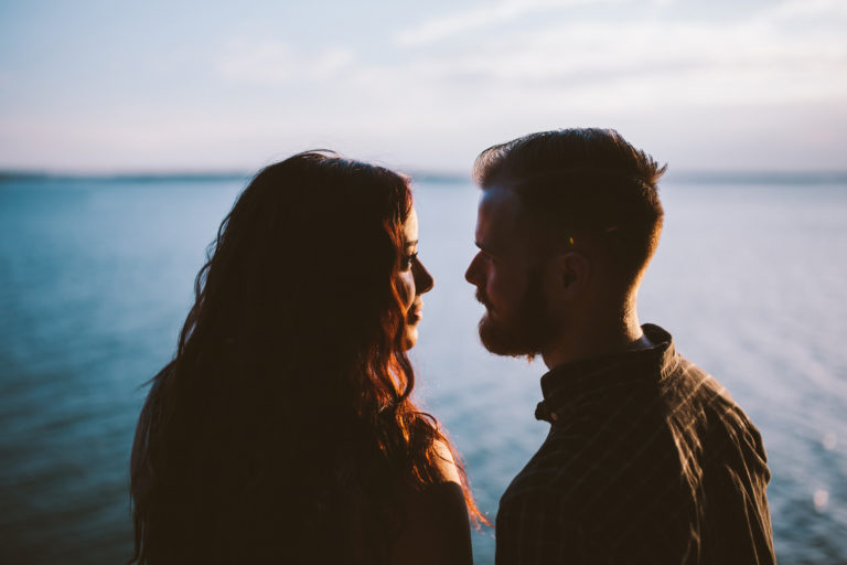 A couple looking at each other in the eyes in front of the ocean.