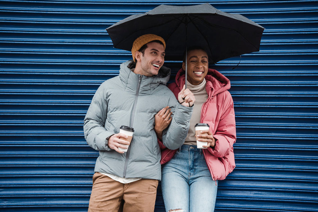 Man and woman embrace coupes therapy technique, smiling and holding an umbrella together.