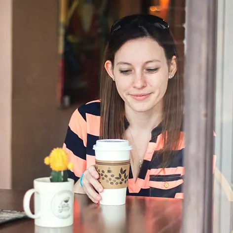 Woman sits in a coffee shop, pensive but pleased