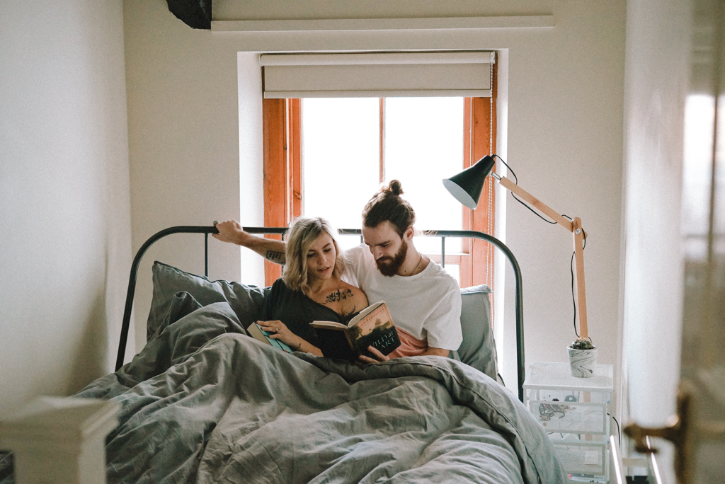 A couple reading in bed together, demonstrating the love style of activity.