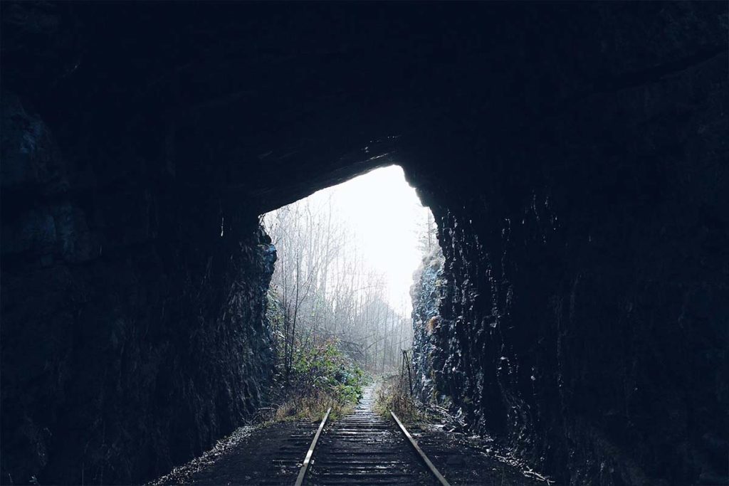 A tunnel with train tracks leading to nature, the light at the end of the tunnel after undergoing couples therapy that was worth it.