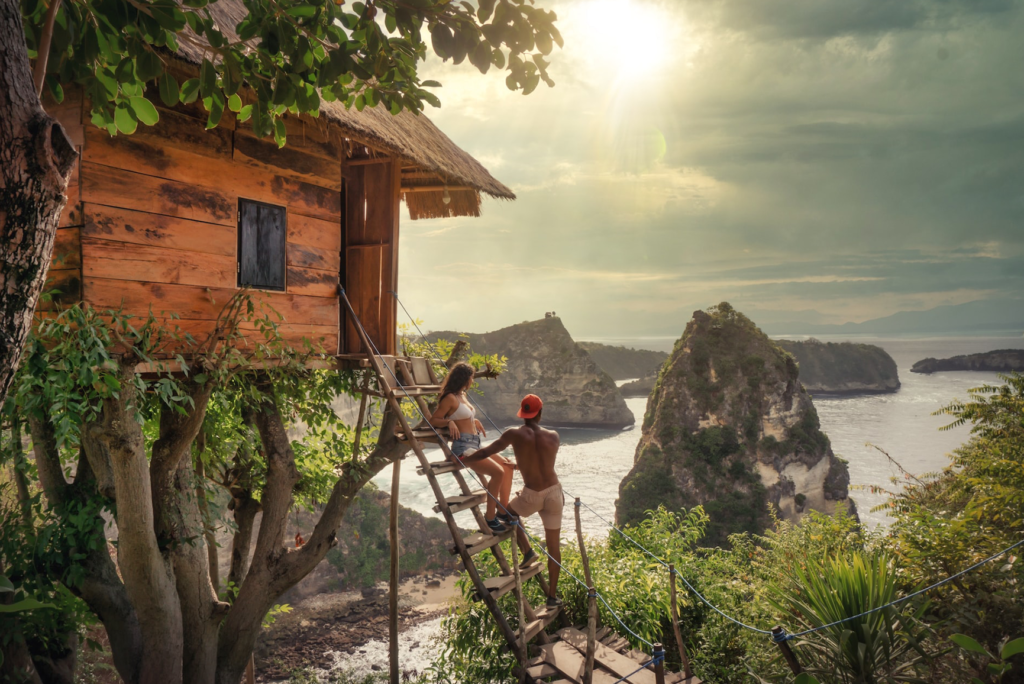 A man and a woman stand on a ladder in a beautiful treehouse at their honeymoon, it's practically perfect.