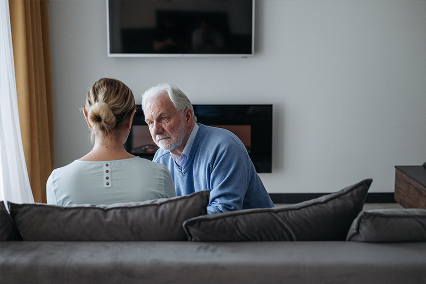 An elderly man kneels in front of his wife in sympathy, he's empathizing with her pain after he damaged their relationship.