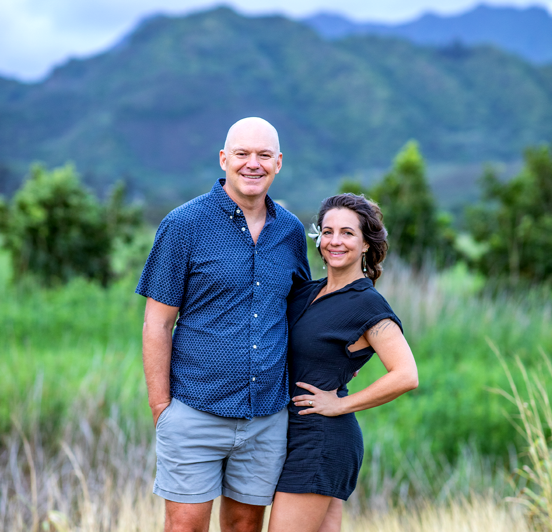 Intensive Couples Therapy Retreat in Hawaii hosts Figs and Teale standing in front of beautiful Hawaiian mountains.
