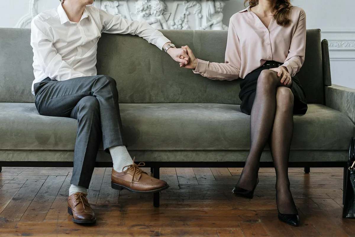 A couple who did find the right therapist holding hands on their psychologist's couch.