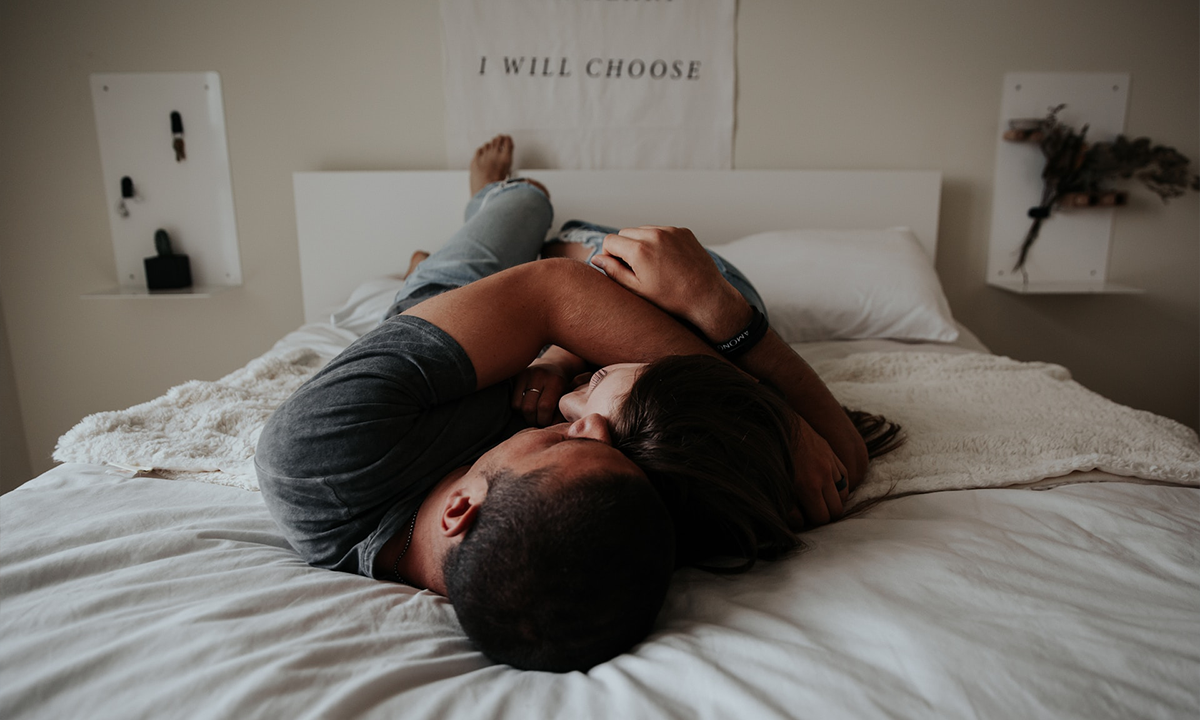 A couple holding each other in bed—they aren't codependent, they just love each other.
