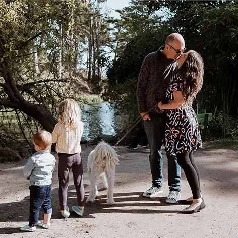 Figs O'Sullivan and Teale Taxis kissing, standing with their kids and dog by the lake.