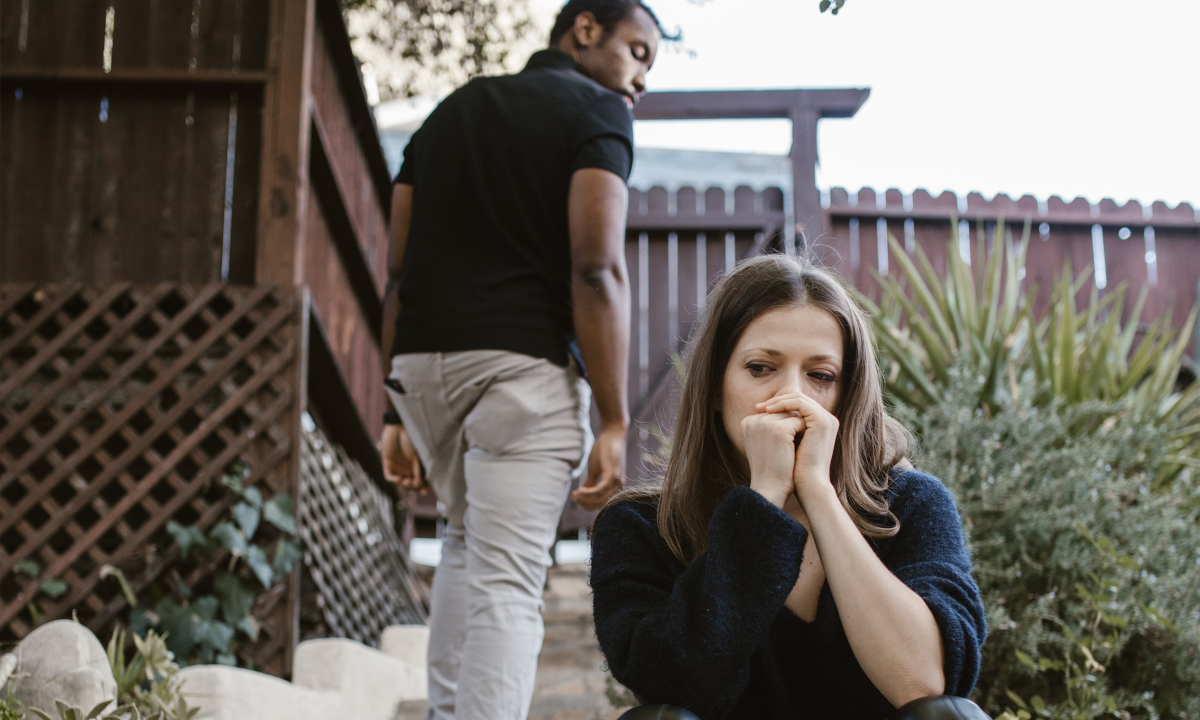 A girl sits on a step as a man walks away from her. She's wondering if her relationship is toxic.