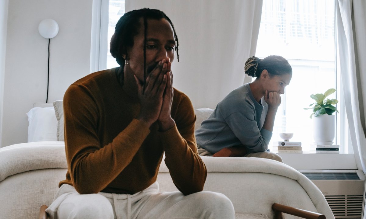 Two people, a black man and a black woman, sit apart on a bed, looking dejected. Can couples therapy help a toxic relationship?